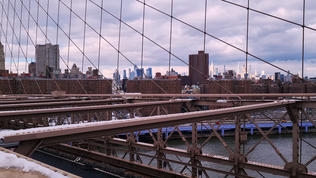 Manhattan skyline as seen from Brooklyn Bridge, showcasing city skyscrapers, iconic architecture, and a cloudy winter day.