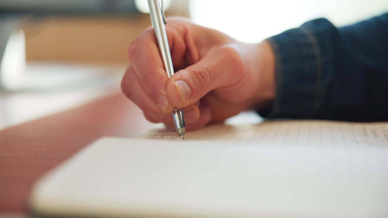 Primo piano di una mano che scrive su un quaderno con una penna