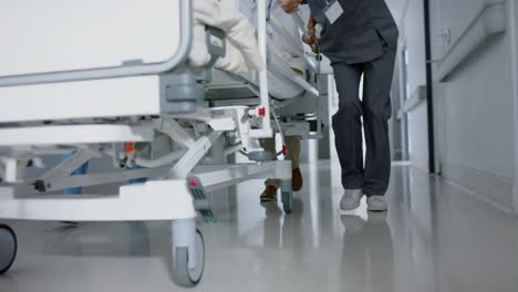 diverse doctor and surgeons walking with patient on hospital bed in slow motion