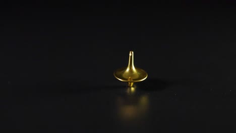 golden spinning top rotating on black surface