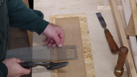 the carpenter cuts metal lattice with a pair of hand shears