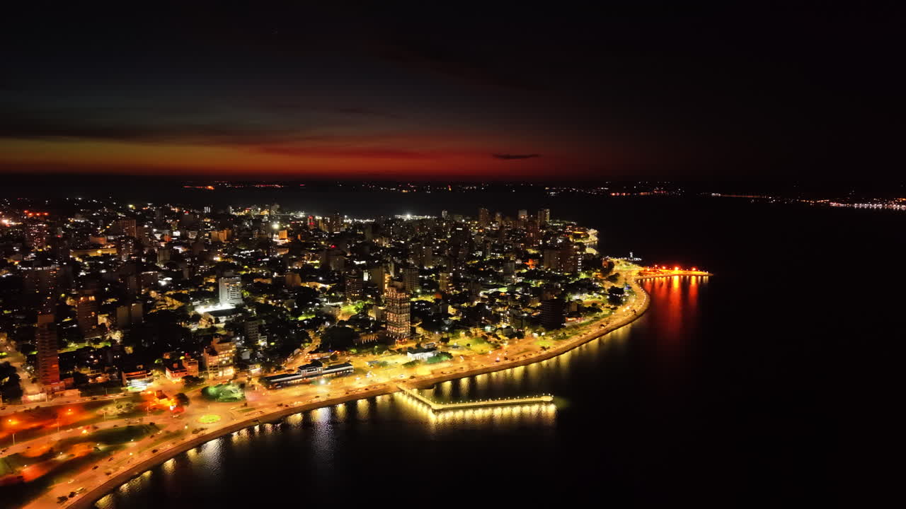Dramatic aerial night view of lit coastline with beautiful urban light trails at the city of Posadas, Misiones, Argentina.