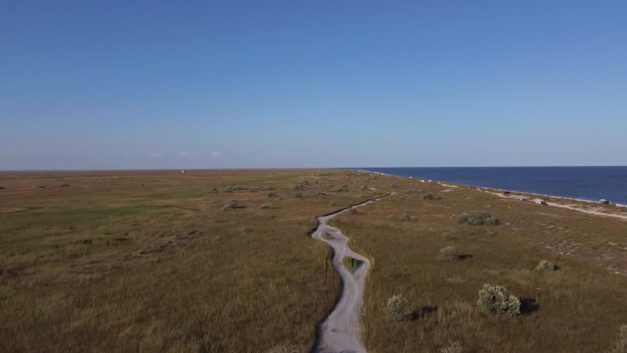 루마니아의 콘스탄타 카운티 근처에 위치한 바두 해변의 해변, 흑해의 은 물, 그리고 지평선에 있는 파란 하늘을 드러내는 기울이는 드론