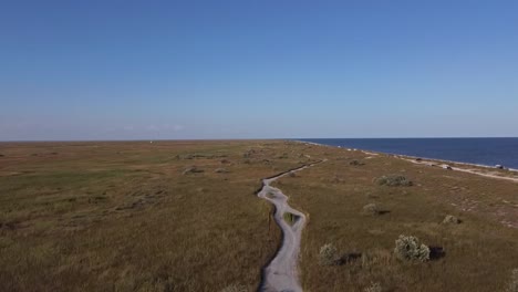 Tilting-drone-shot-revealing-the-beachfront-of-Vadu-Beach,-the-clear-waters-of-the-Black-Sea,-and-the-blue-skies-in-the-horizon,-located-near-Constanta-County-in-Romania