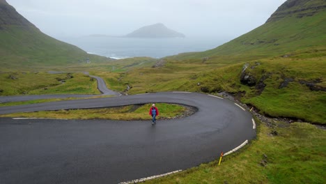 aerial shot of a woman in a faroese sweater showing nordradalsskard and koltur in background