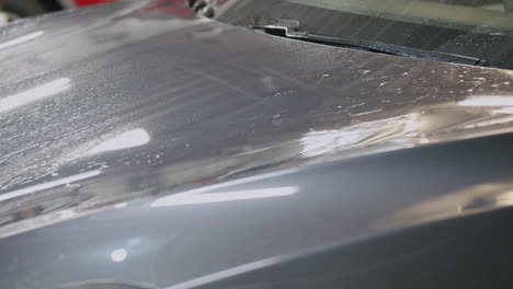 Hand-washing-car-engine-hood-with-yellow-cloth