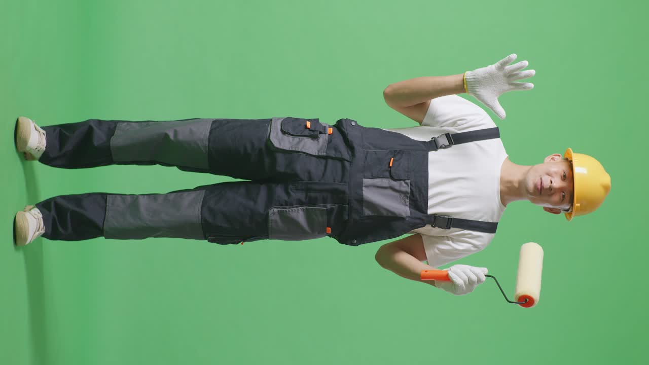 Full Body Of Asian Man Painter Wearing Safety Helmet Smiling And Saying Wow While Standing In The Green Screen Background Studio