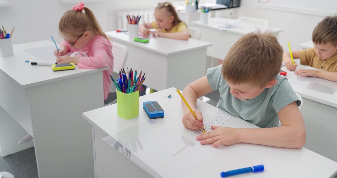 Bambini concentrati che disegnano con le matite in un'aula moderna