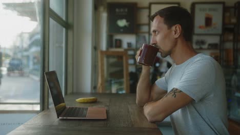 man working at a cafe with a laptop and coffee