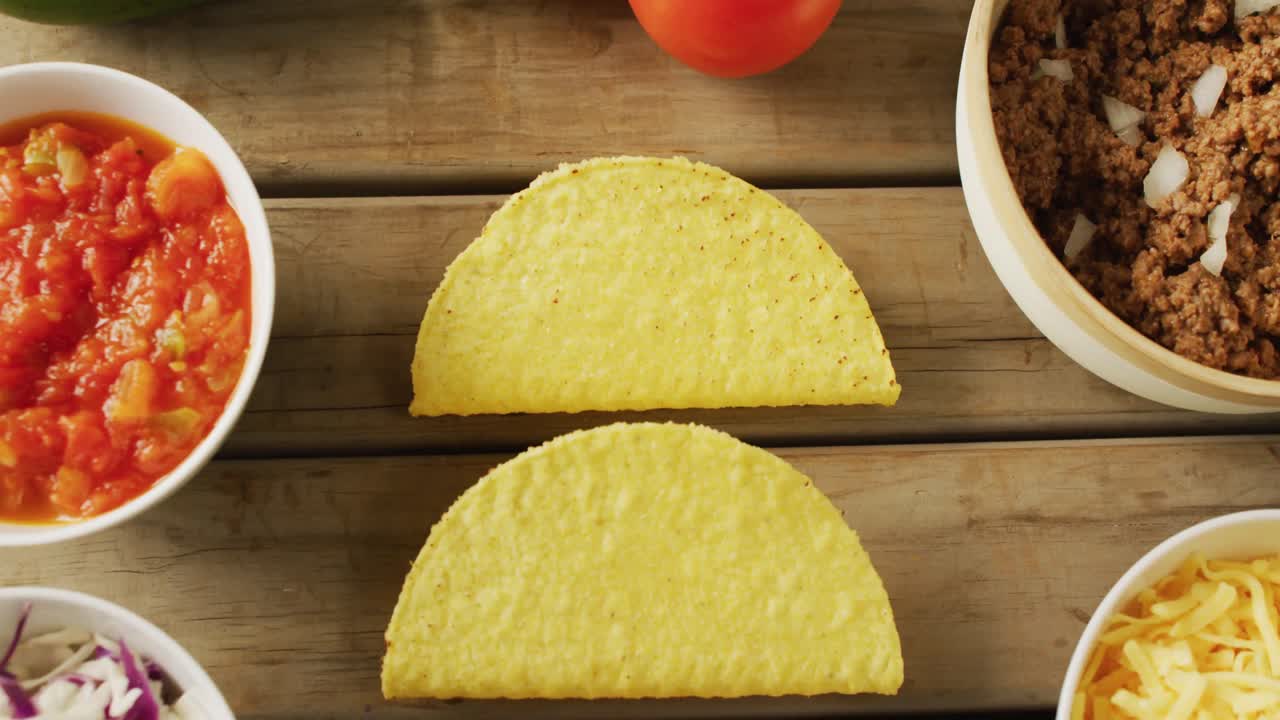 Video di tacos, insalata, carne, limone e altri ingredienti appoggiati su sfondo di legno