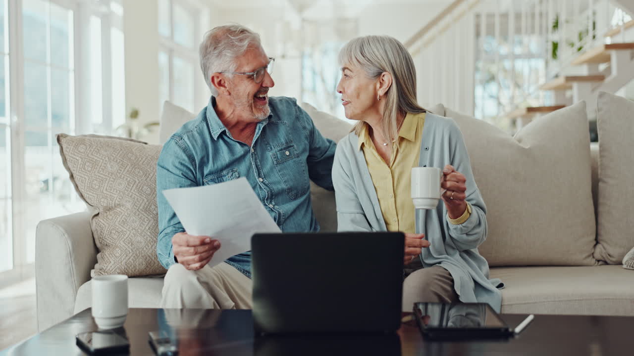Senior Couple Reviewing Documents on Laptop at Home