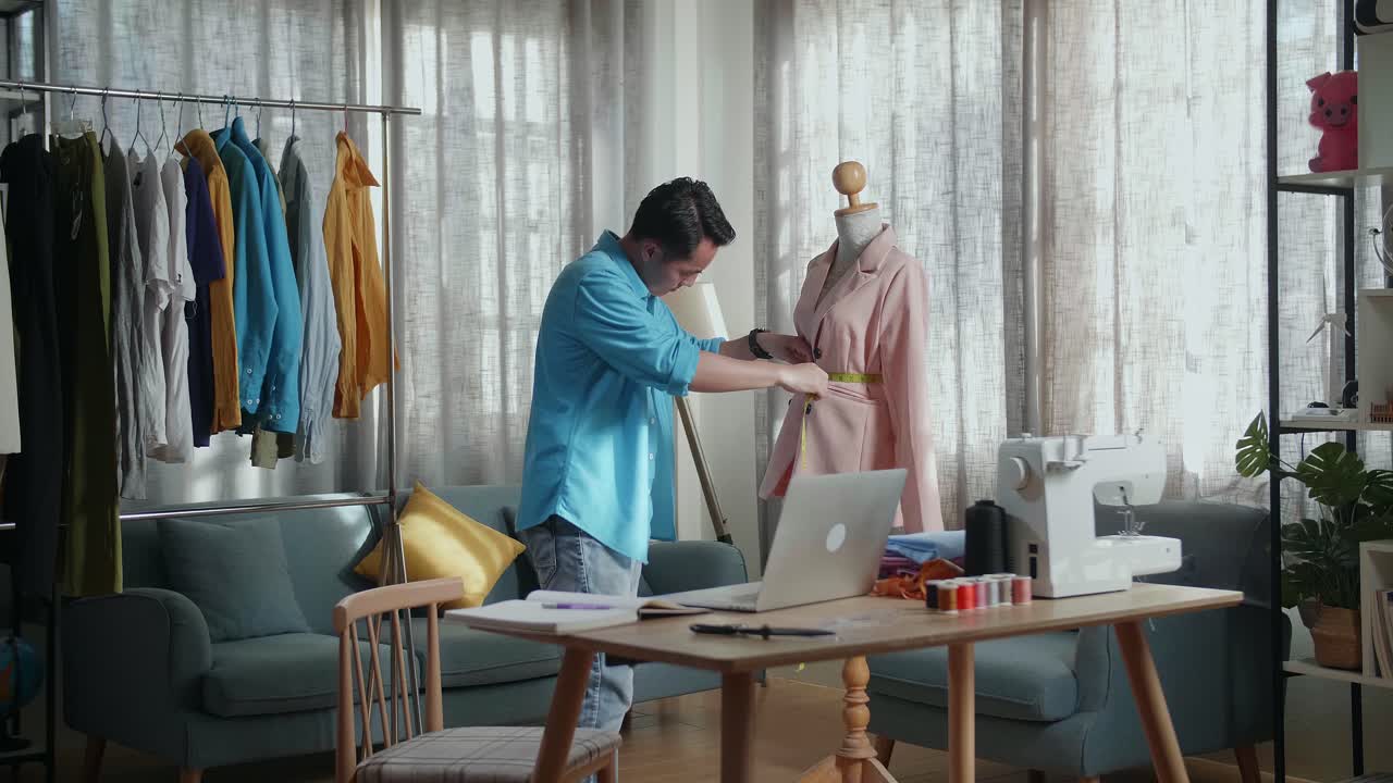 스튜디오에서 옷을 디자인하는 동안 마네킨에 재을 측정하는 바느질 기계와 함께 아시아 남성 디자이너