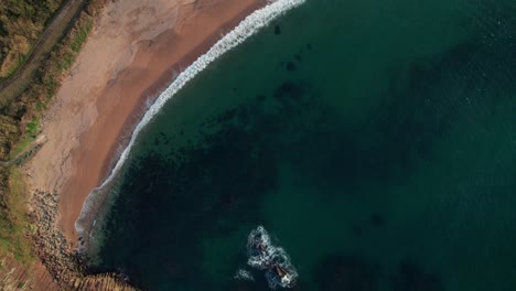 Aerial-drone-travels-top-down-white-sand-pristine-beach-of-kyotango-kyoto-Japan-travel-destination,-summer-in-Asia,-blue-waves-crushing-unpolluted-light-green-cliff-coastline