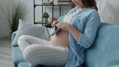 pregnant woman holding baby shoes on her belly