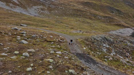 Two-people-hiking-up-a-rocky-mountain-in-lake-Naret,-Switzerland