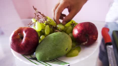 man taking grapes for fruit salad