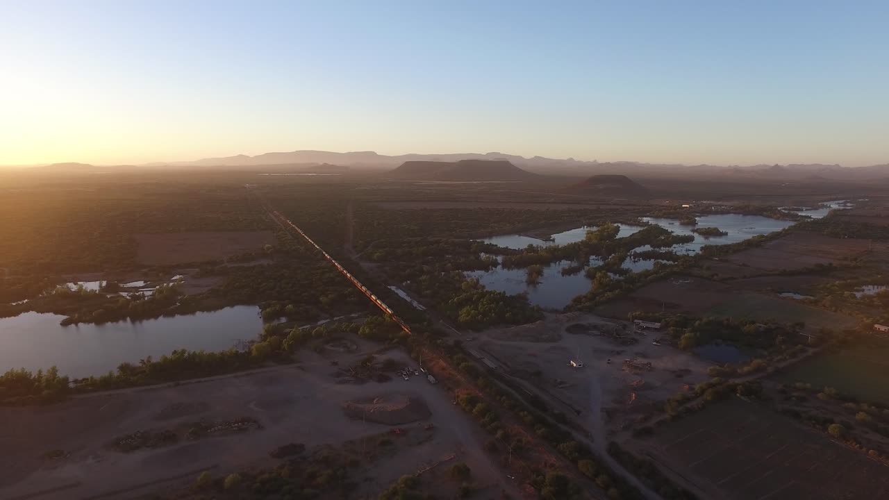 toma aérea de un gran tren de carga en sonora al atardecer