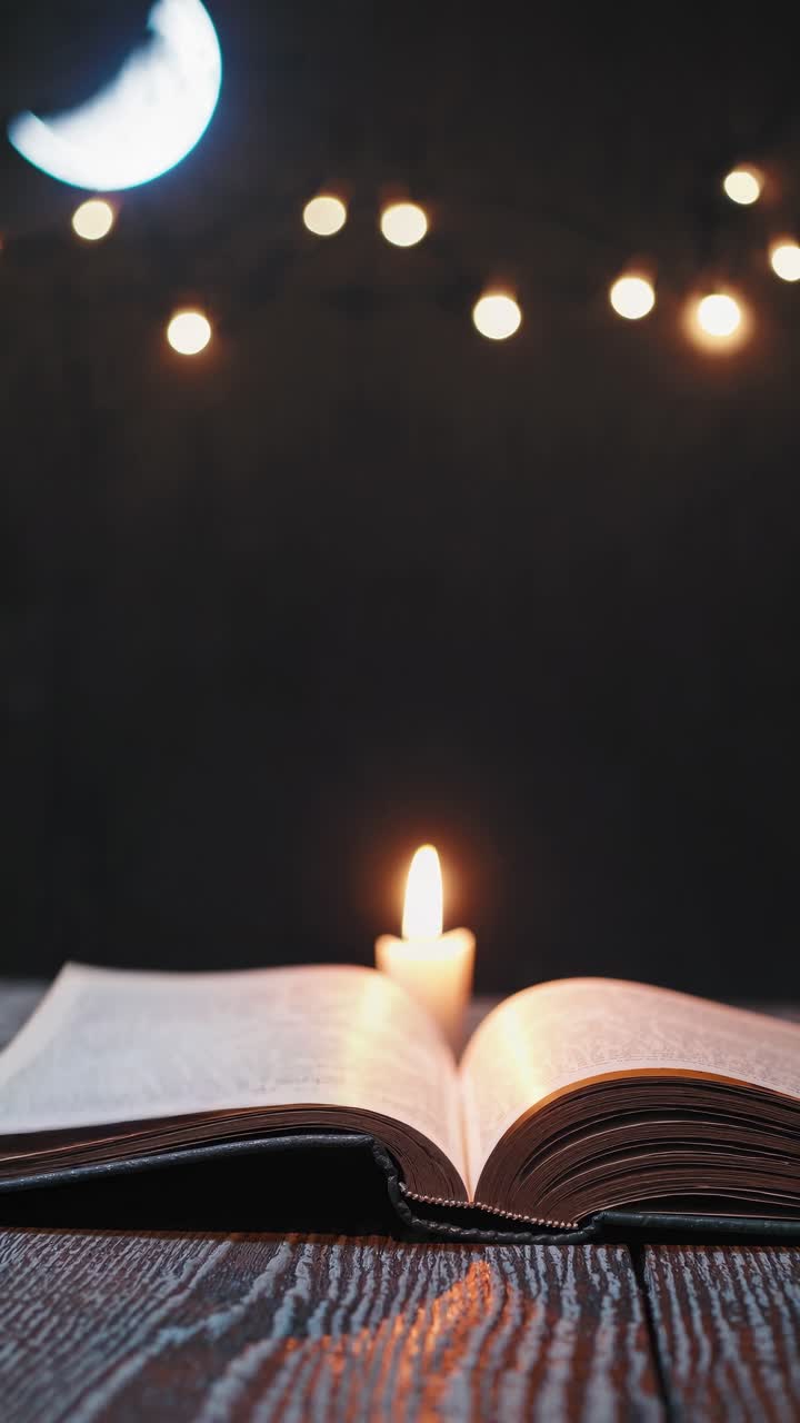 A mystical video scene with an open book and candle on a wooden table