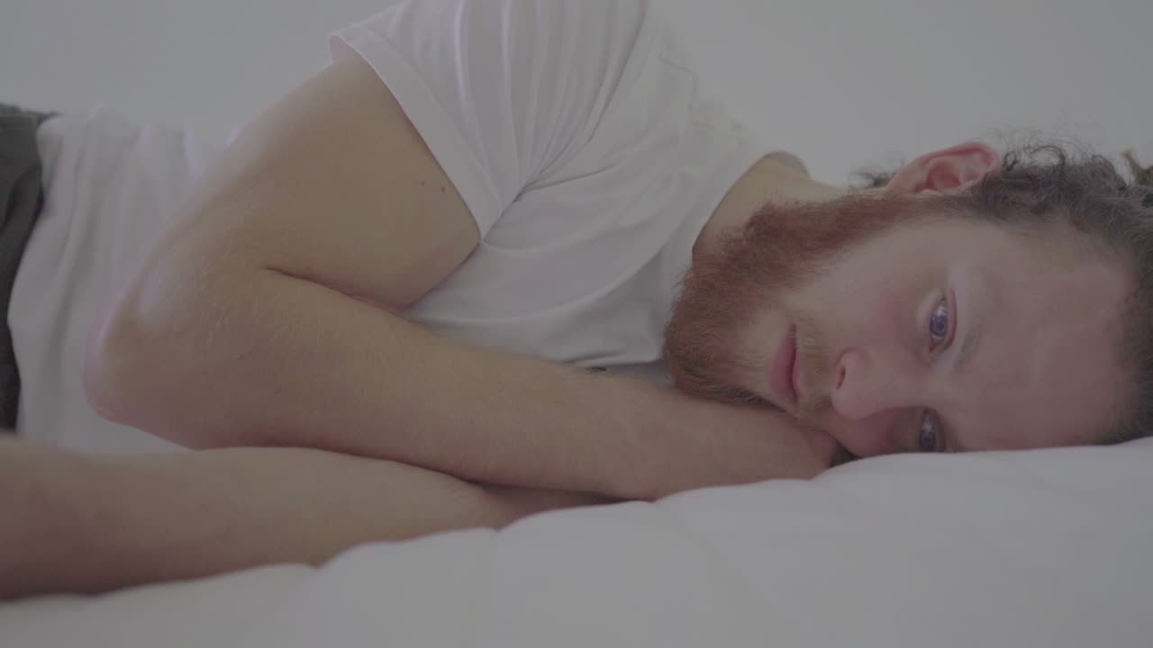 침대에 누워 있는 아름다운 파란 눈을 가진 젊고 잘생긴 남자