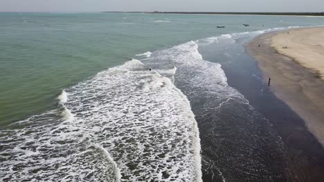 bakau, the gambia panning right over the sea beach with tourists swimming in the ocean