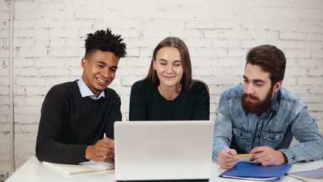 Feliz-Y-Atractivo-Grupo-étnico-Mixto-De-Jóvenes-Profesionales-Sonriendo-Mientras-Tienen-Una-Reunión-De-Negocios-O-Una-Discusión-A-Través-De