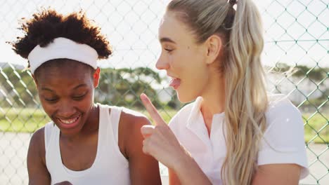 video of happy diverse female tennis players sitting, talking and resting after match