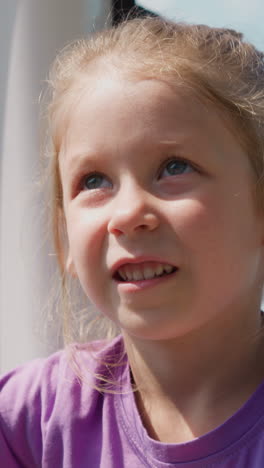 thoughtful little girl looks up riding gondola with glass windows following moving mechanism on safe poma lift at mountain resort closeup slow motion