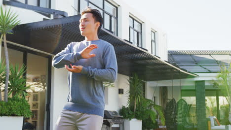 Video-of-relaxed-biracial-man-exercising-tai-chi-in-garden