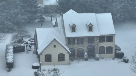 large single family house snow-covered during snowstorm in suburb of usa