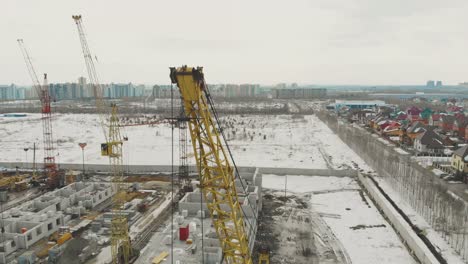 grúa de construcción amarilla cercana contra el distrito de cabañas