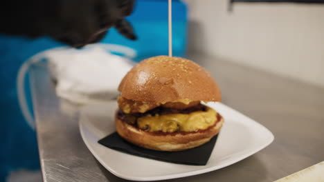 chef putting the wooden stick inside the burger ready to be served