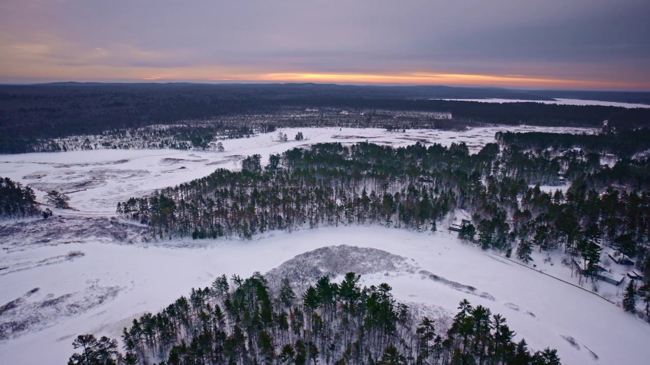 Drönarbild över snötäckt kustlinje längs Lake Superior med isiga vågor, oländig strand, frusen terräng, vildmarken i Upper Peninsula och filmiskt vinterlandskap.