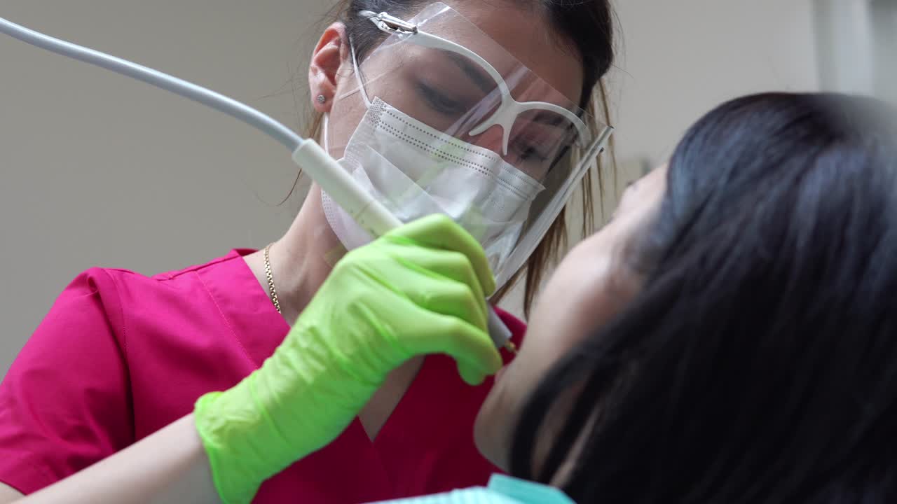 Woman at the dental hygienist getting professional tooth whitening and ultrasound cleaning. Shot in 4k