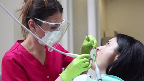 mujer en el higienista dental recibiendo blanqueamiento dental profesional y limpieza por ultrasonido. dentista usando eyector de saliva o bomba dental para evacuar saliva. filmado en 4k