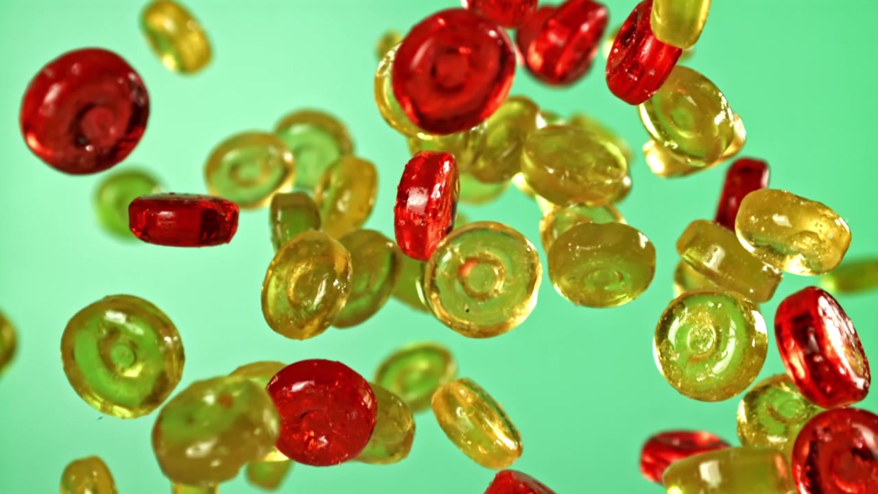 Caramelle colorate che cadono e rimbalzano su sfondo verde