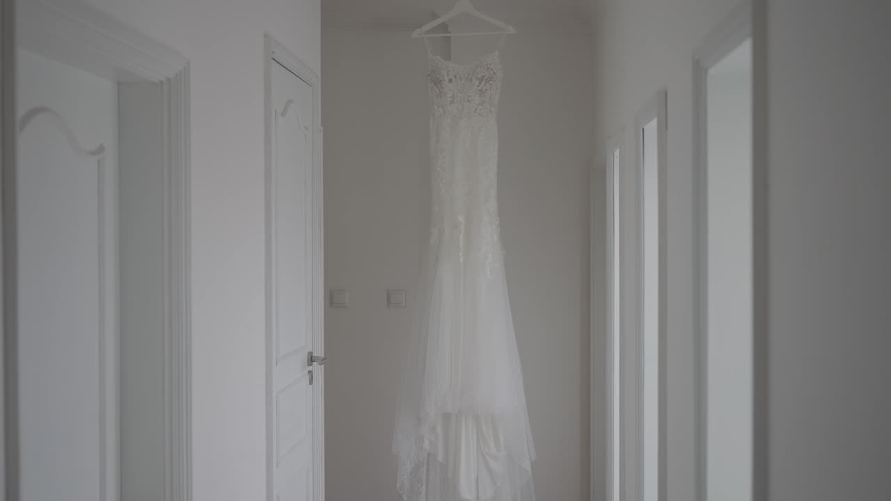 Abito da sposa bianco appeso tra le porte nel corridoio interno minimalista