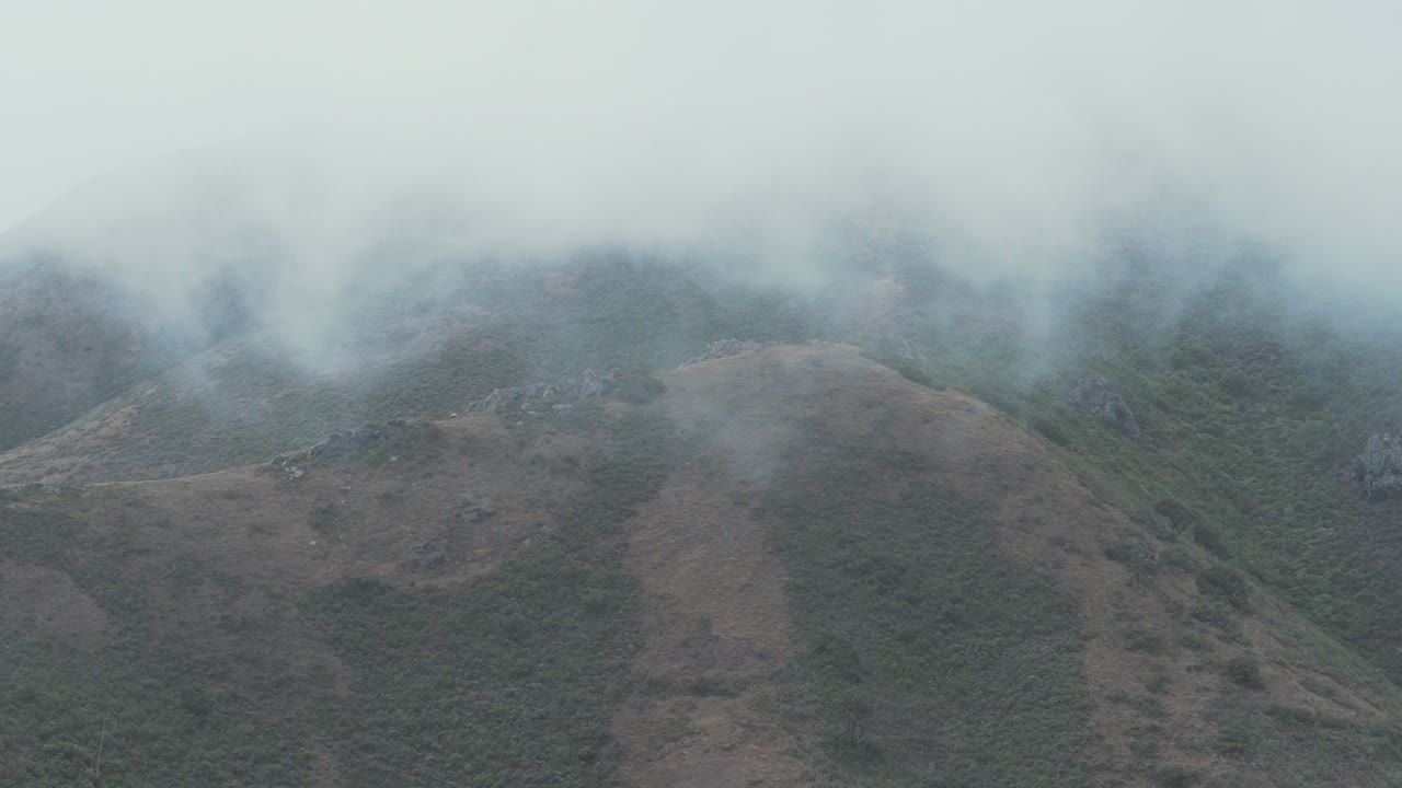 la niebla rueda por la ladera de una montaña en la costa de california