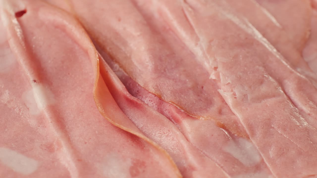 Ham italian mordatella, man Slices Of Traditional Italian antipasti mortadella sausage on a wooden cutting board, close up macro of chicken or turkey jamon, fat breakfast dish.