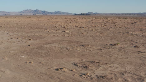 flying low over bleak and empty desert landscape with distant mountains