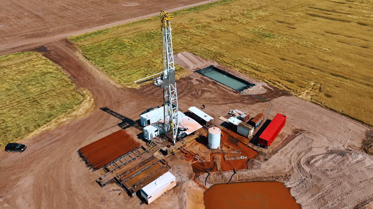Gas extraction industry in the vast field. Derrick is in the middle of the drilling site. Aerial view.