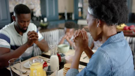 Happy-african-american-family-praying-before-breakfast,-in-slow-motion