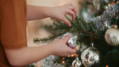 close up of young boy hanging christmas bauble on tree