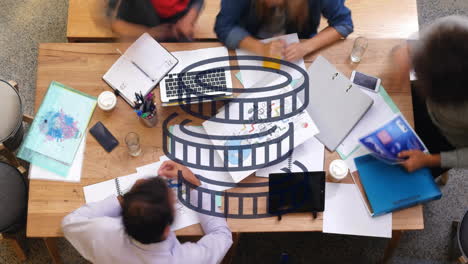 film reel animation over group of people collaborating at desk with documents