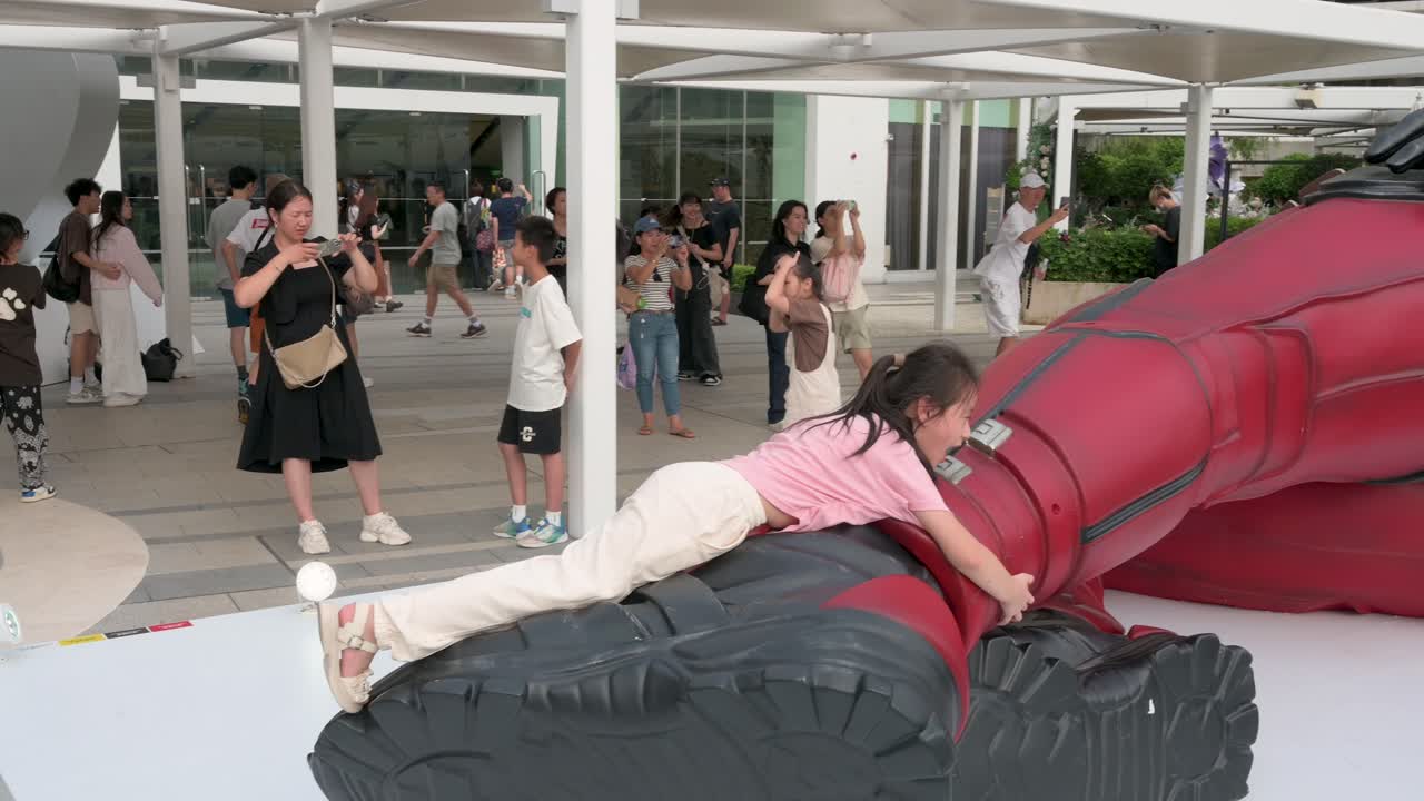 The Hong Kong skyline frames an 8-meter Deadpool installation, where locals, tourists, and children gather to take photos while promoting Disney’s release of the "Deadpool and Wolverine" movie.