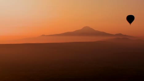 Gorgeous-aerial-shot-of-a-hot-air-balloon-silhouetted-against-distant-mountains-in-Cappadocia-Turkey-1