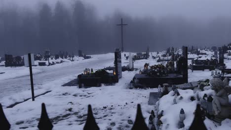 a polish graveyard in winter, featuring tombstones revealed behind a spiky metal fence