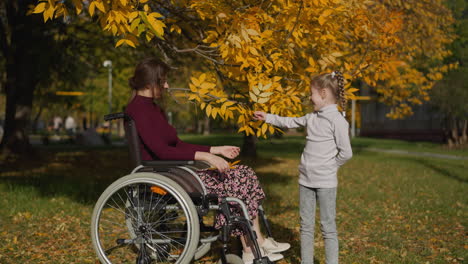 Madre-En-Silla-De-Ruedas-Descansa-Con-Su-Hija-En-El-Jardín-De-Otoño