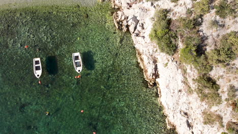 beautiful white row boats tied by the mountain shoreline in greece - top view