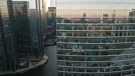 Aerial-view-flying-in-middle-of-mirroring-buildings-of-Loop,-revealing-the-Chicago-river