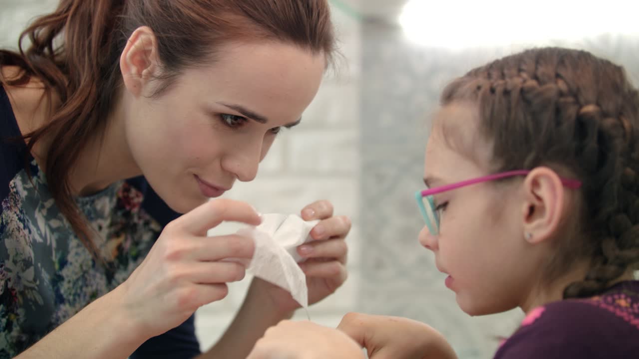 mamá limpia la cara hija. niña comiendo cítricos con mamá. mañana comida saludable